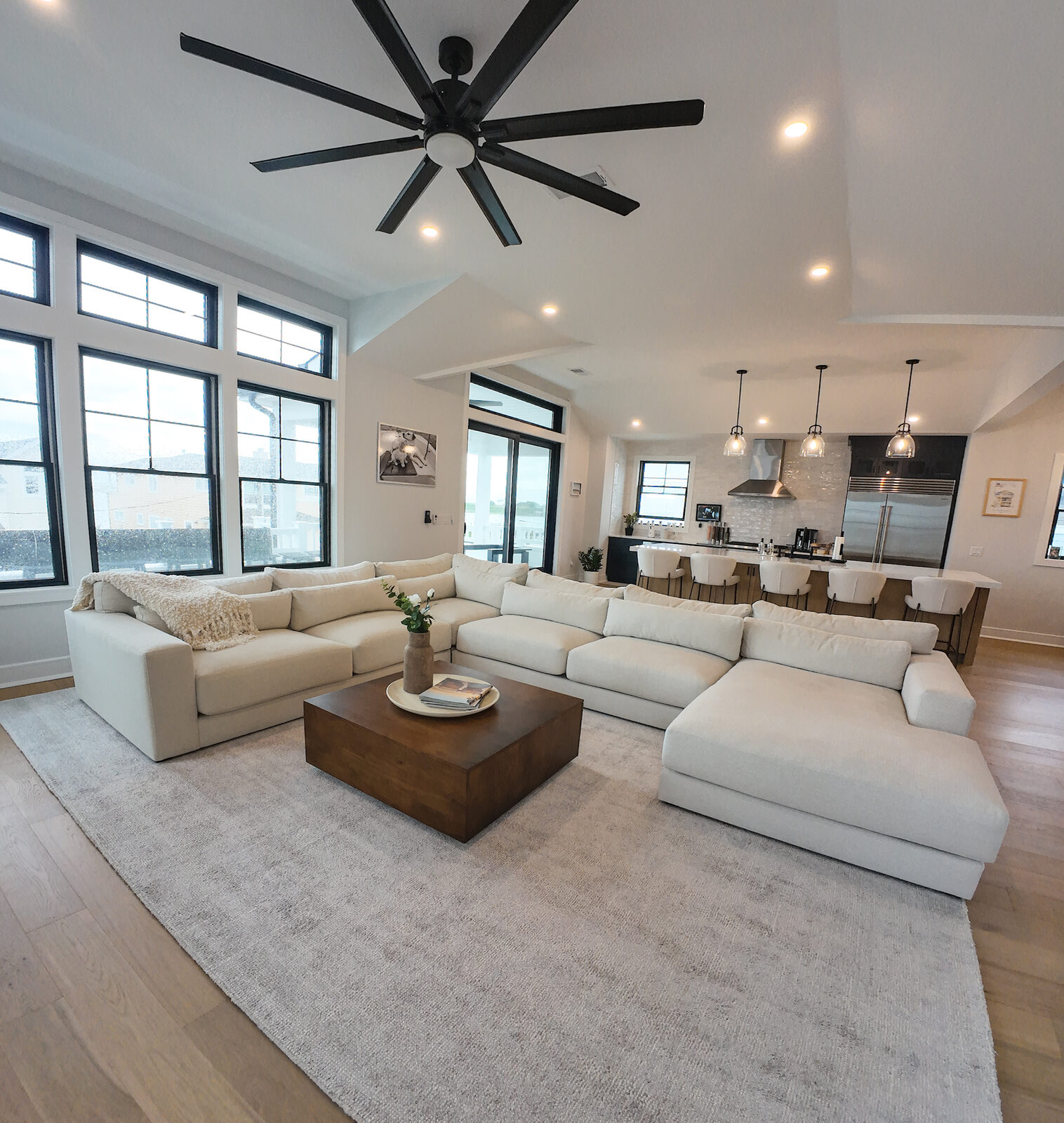 Great room with oversized cream sectional, walnut coffee table, and black framed windows
